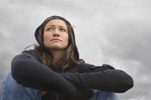 Girl sitting and contemplating on a background of a cloudy sky